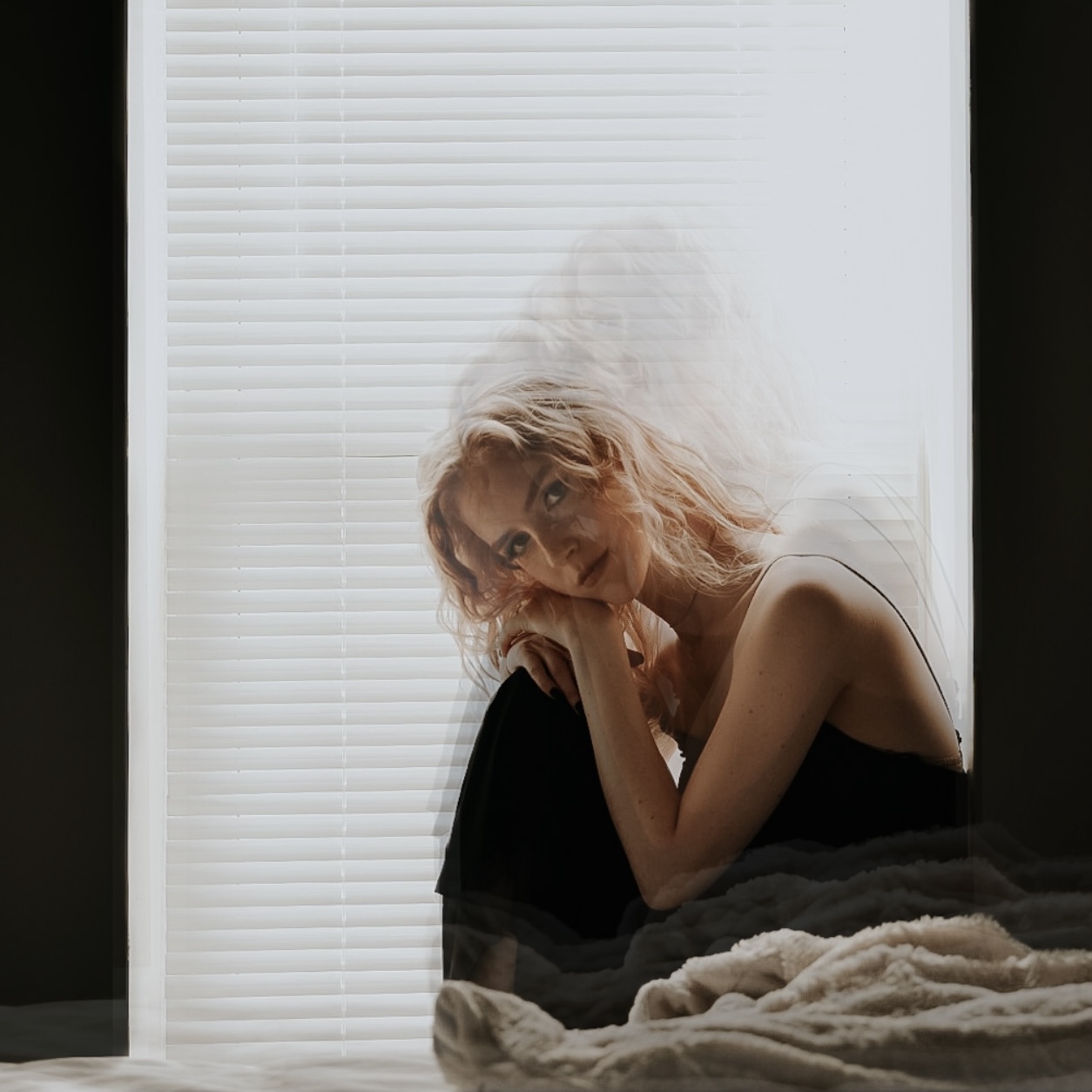 Paige Warner seated in front of a window with closed blinds.